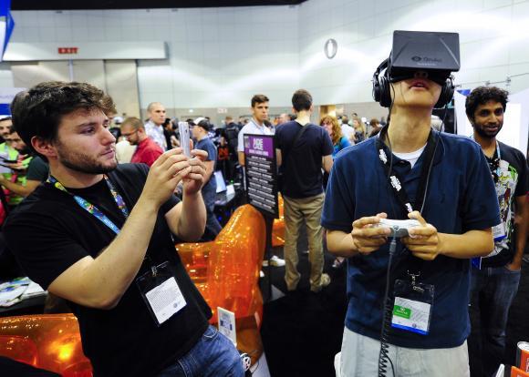 Rectal software designer Julian Kantor takes a picture of Jonathan Feng as he uses the Oculus Rift virtual reality headset to experience his program during E3 in Los Angeles