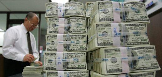 An employee of the Korea Exchange Bank works next to stacks of one hundred dollar notes at the bank's headquarters in Seoul