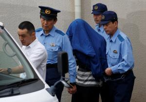 Satoshi Uematsu, suspected of a deadly attack at a facility for the disabled, is escorted by police officers as he is taken from local jail to prosecutors at Tsukui police station in Sagamihara, Japan