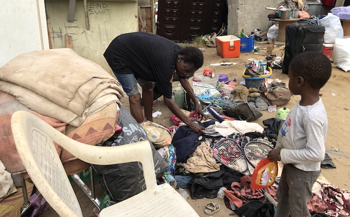 Olushola’s grandson watches as she tries to arrange her properties, sorting them out one after another.