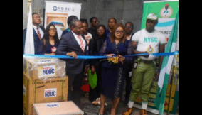 Mary Nwaeke, Director, NDDC Liaison Office, Abuja, (middle) cuts the tape to hand over broadcast equipment to the National Youth Service Corps, at the NYSC National Directorate Headquarters in Abuja. With her is  Emeka Mgbemena, the NYSC Director, Media