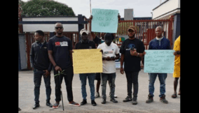 Placard-carrying community people at the gates